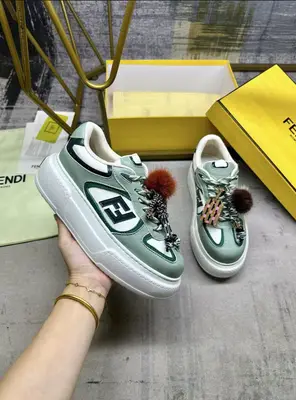 FENDI Match繫帶運動鞋。淺綠色面料，帶綠色細節。側邊飾有撞色皮革FF貼花，白色和綠色登山鞋帶。橡膠厚鞋底，後跟處飾有超大凸紋壓花FENDI字樣。鞋舌上飾有金屬環掛飾：右鞋上飾有帶撞色貂毛細節和金色金屬FF圖案手鍊的編繩小玩偶。左鞋