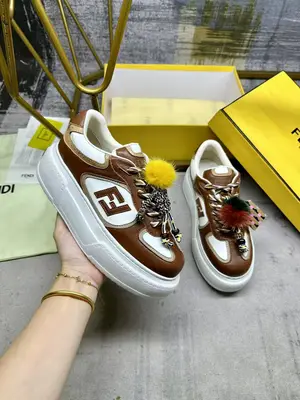 FENDI Match繫帶運動鞋。棕色面料，帶米色細節。側邊飾有撞色皮革FF貼花，白色、米色和棕色登山鞋帶。橡膠厚鞋底，後跟處飾有超大凸紋壓花FENDI字樣。鞋舌上飾有金屬環掛飾：右鞋上飾有帶撞色貂毛細節和金色金屬FF圖案手鍊的編繩小玩偶。