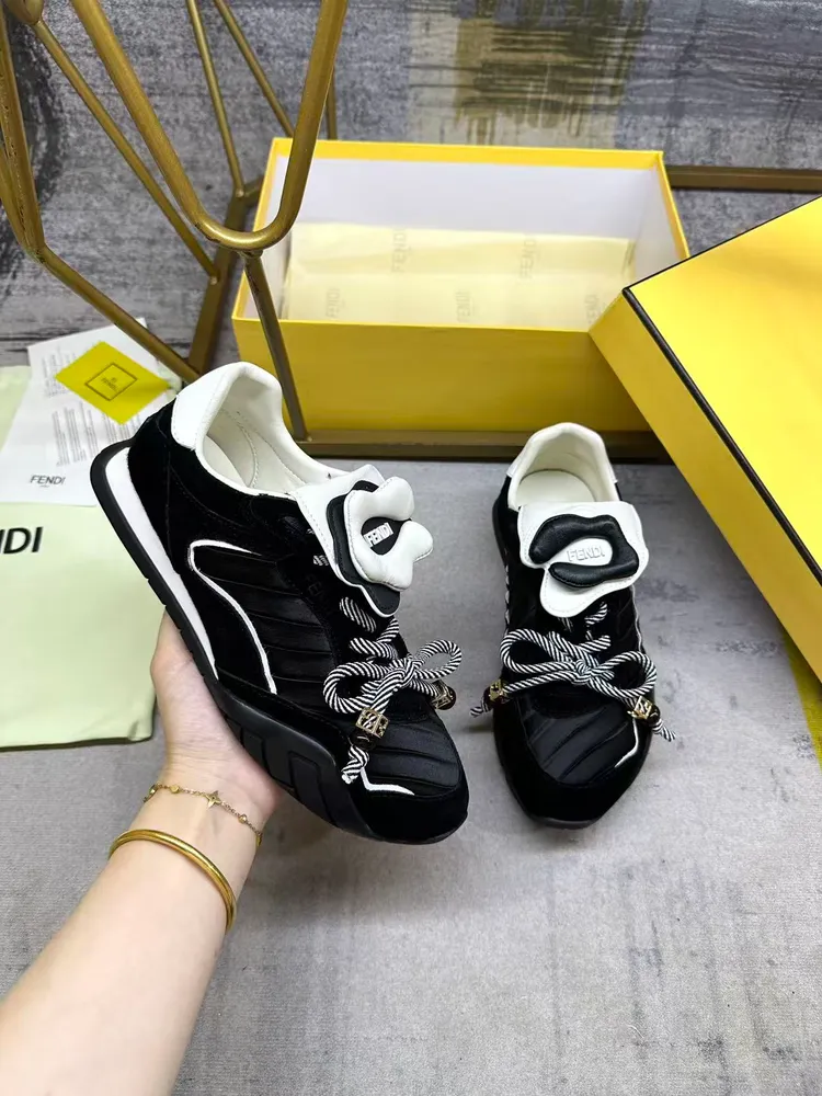 FENDI Wave Pulse繫帶低幫運動鞋。黑色緞面材質，飾有褶襉和同色系絨面料嵌飾。白色皮料後跟鞋領。鞋舌為可拆卸摺疊式設計，飾有立體同色花冠飾片。彈力鞋帶搭配拼色管狀鞋帶，飾有黑色珠飾和金色FF圖案立方元素。鞋側與鞋舌飾有立體橡膠標
